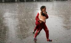 طفلة من غزة تحمي شقيقها من المطر في أحد مراكز النزوح.jpg