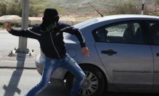 شاب يلقي الحجارة على سيارة مستوطن
