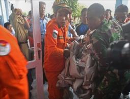 عناصر من سلاح الجو الإندونيسي يحملون أجزاء من حطام الطائرة (الفرنسية)