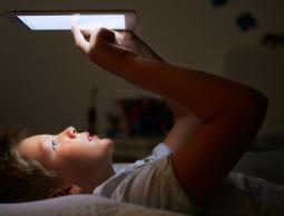 طفل يلعب في جهاز إلكتروني قبل النوم