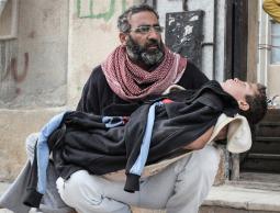 والد يحمل إبنه المصاب في سوريا (الأرشيف)