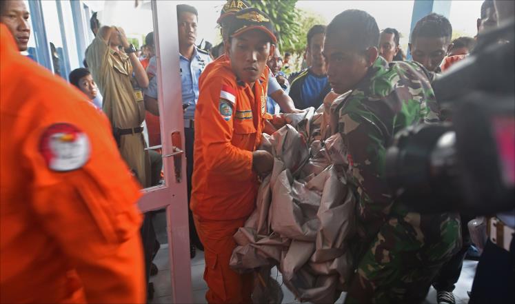 عناصر من سلاح الجو الإندونيسي يحملون أجزاء من حطام الطائرة (الفرنسية)