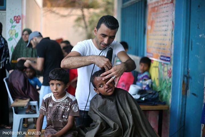 حلاق يقص شعر أحد الأطفال النازحين إلى المدارس (أرشيف)