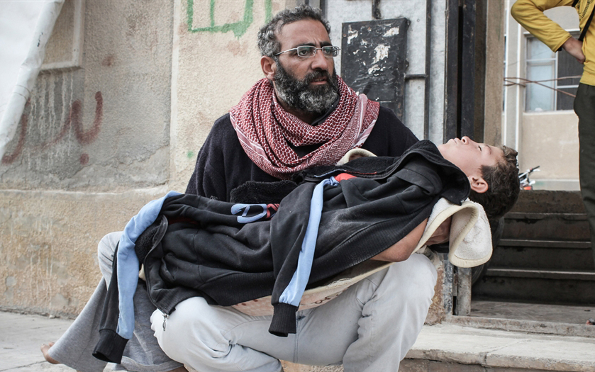 والد يحمل إبنه المصاب في سوريا (الأرشيف)